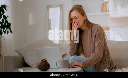 Caucasian shocked woman in glasses looking at laptop reading bad news close mouth with hands holding head with shock failure student girl lost with Stockfoto