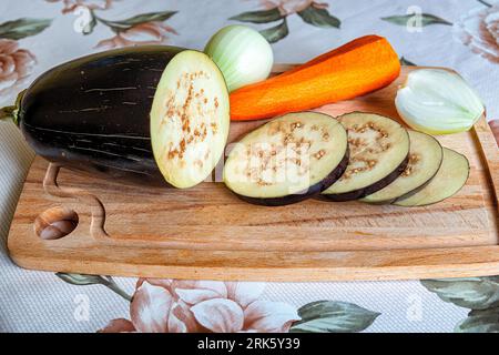 Still life of eggplant, carrots and onions on a cutting board Stockfoto