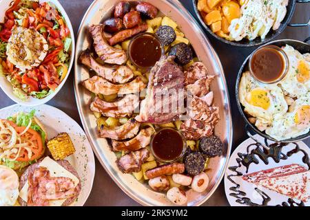 A variety of Spanish cuisine featuring barbecue ribs, fried eggs, and potatoes with sauces artfully arranged on a plate Stock Photo