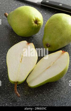 Frische ganze und halbierte Süßzuckerbirne aus nächster Nähe auf einem Schneidebrett Stockfoto