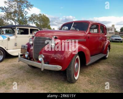 Alte rote Chevrolet Chevy Master Limousine von General Motors aus dem Jahr 1939 auf dem Rasen. Natur, Gras, Bäume. CAACMACH 2023 Oldtimer-Show. Stockfoto