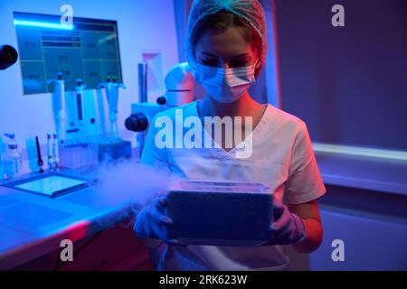 Woman embryologist holds tank with liquid nitrogen in her hands Stockfoto