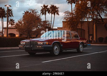 Eine klassische rote Cadillac-Limousine aus dem Jahr 1991, die in einer malerischen Umgebung vor grünen Bäumen geparkt ist Stockfoto