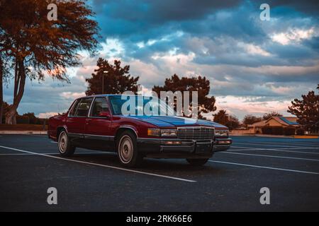 Eine klassische rote Cadillac-Limousine aus dem Jahr 1991, die in einer malerischen Umgebung vor grünen Bäumen geparkt ist Stockfoto