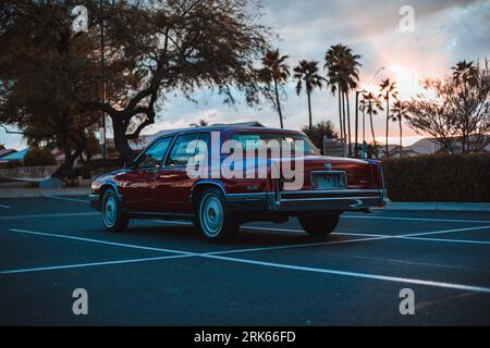 Eine klassische rote Cadillac-Limousine aus dem Jahr 1991, die in einer malerischen Umgebung vor grünen Bäumen geparkt ist Stockfoto