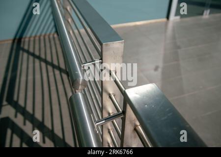 Die Brüstungsgeländer des modernen Gebäudes, Details aus poliertem und satiniertem Stahl, schützt vor dem Absturz. Zeitgenössische Architektur. Geometrie des Handlaufs. Stockfoto