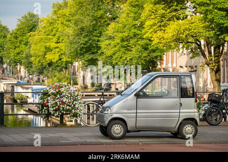 Amsterdam, The Netherlands, 24.08.2023, Dutch two-seat vehicle Canta LX, classified as mobility aid, parked at the bridge by the canal Stock Photo