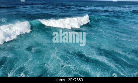 An aerial view of turquoise waves in the sea on a sunny day Stockfoto