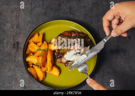 A closeup of a person cutting a chicken steak with a knife Stock Photo