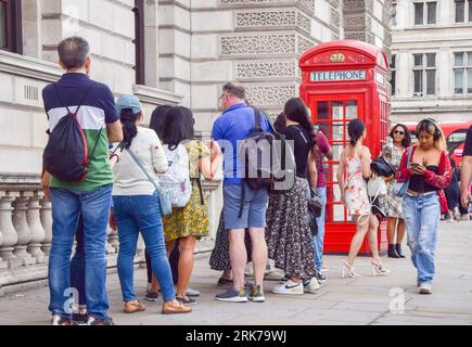 London, Großbritannien. August 2023. Touristen warten auf Selfies neben einer Telefonbox auf dem Parliament Square. BT hat 1000 rote Telefonboxen für die „Adoption“ in Großbritannien für jeweils nur 1 £ vor dem 100. Jahrestag zur Verfügung gestellt. Die originale Inkarnation des berühmten roten Kiosks, der K2, wurde 1924 vom Architekten Sir Giles Gilbert Scott entworfen und als die Nutzung öffentlicher Telefone im Laufe der Jahre abnahm, bot BT die Möglichkeit, die Kioske verschiedenen Organisationen, Gemeinschaften und Einzelpersonen zu nutzen. Quelle: Vuk Valcic/Alamy Live News Stockfoto