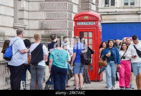 London, Großbritannien. August 2023. Touristen warten auf Selfies neben einer Telefonbox auf dem Parliament Square. BT hat 1000 rote Telefonboxen für die „Adoption“ in Großbritannien für jeweils nur 1 £ vor dem 100. Jahrestag zur Verfügung gestellt. Die originale Inkarnation des berühmten roten Kiosks, der K2, wurde 1924 vom Architekten Sir Giles Gilbert Scott entworfen und als die Nutzung öffentlicher Telefone im Laufe der Jahre abnahm, bot BT die Möglichkeit, die Kioske verschiedenen Organisationen, Gemeinschaften und Einzelpersonen zu nutzen. Quelle: Vuk Valcic/Alamy Live News Stockfoto