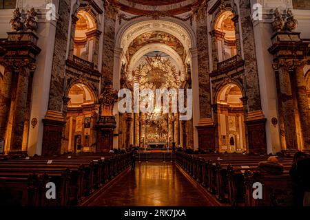 An interior view of a stunning cathedral featuring a golden stained glass window and rows of wooden pews Stockfoto