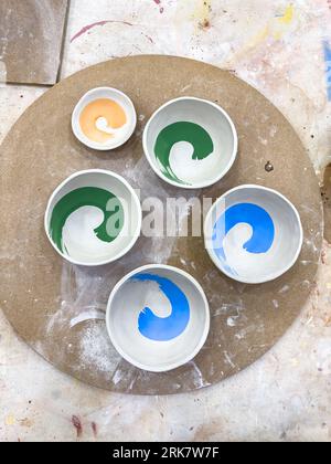 A selection of greenware ceramics bowls decorated with underglaze and ready for the first bisque fire Stock Photo