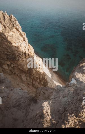 A vertical shot of rocky cliffs over the water near Pissouri trail, Cape Aspro, Pissouri, Cyprus Stock Photo