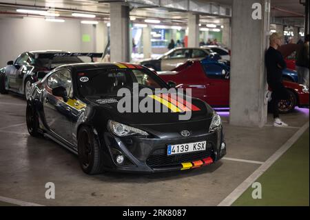 Vorderansicht eines schwarzen japanischen Sportwagens Toyota GT86 mit farbigen Streifen, der in der Tiefgarage geparkt ist Stockfoto