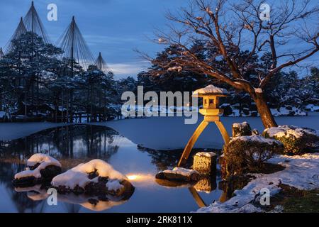 Kasumi-Teich im Kenrokuen-Garten in Kanazawa, Japan, bei Nacht und im Winter, schneebedeckt. Die Steinlaterne, Kotoji-toro, steht im Vordergrund. Stockfoto