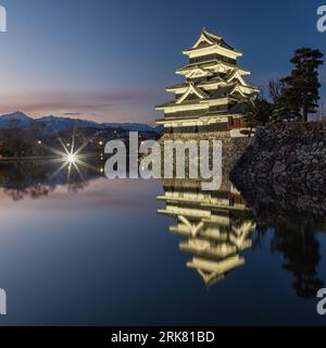 Matsumoto Castle in Japan is lit up at night. It reflects in the moat that surrounds it. Stockfoto