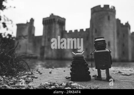 Two toy robots standing side by side on a rocky surface, appearing to interact with one another Stock Photo