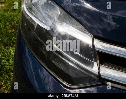 Moderne Autoscheinwerfer mit Himmel Reflexion auf ihnen. Autoscheinwerfer in Nahsicht Stockfoto