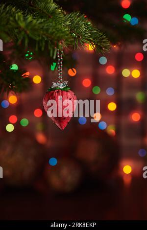 Christmas decoration fabric strawberry on Christmas tree, dark colorful bokeh background Stock Photo