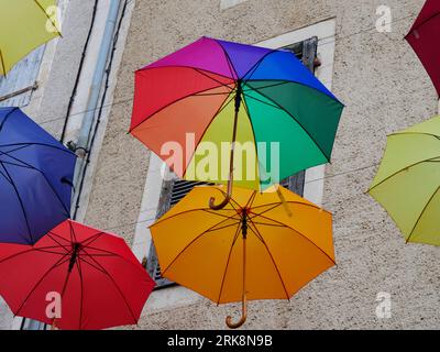 colorful floating umbrellas in the street in Puy l'Eveque. Rainbow colored umbrella sky projet in Puy-l'Évêque Stock Photo