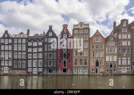 Stadtgebäude von Amsterdam neben den Kanälen in den Niederlanden mit farbenfrohen Fassaden, historischen Giebeln und klassischen holländischen Stadthäusern. Stockfoto