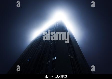 Großer Wolkenkratzer im Nebel, der in Wolken geht Stockfoto