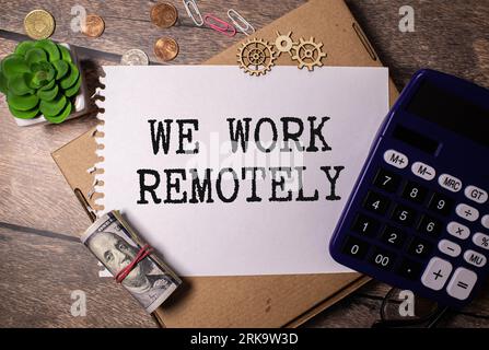 WORK REMOTELY text on a sticky with pen on the wooden background. Stock Photo