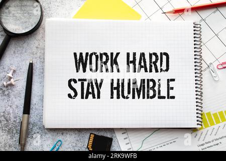 Wortzitate der ARBEIT HART BLEIBEN BESCHEIDEN auf bunten Memopapieren mit Holzhintergrund Stockfoto