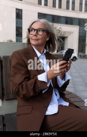 Porträt einer gepflegten, charmanten Unternehmerin reifer Jahre im braunen Anzug Stockfoto