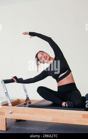 Woman doing Pilates exercise on pilates reformer bed.  Stock Photo