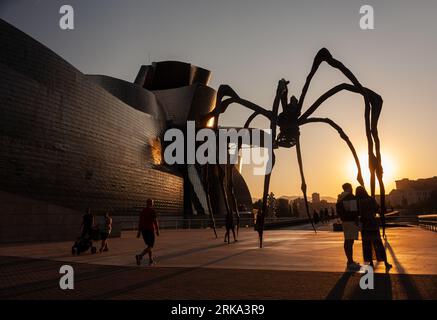 Bilbao, Spanien - 02. August 2022: Ein paar Touristen machen ein Selfie bei Sonnenuntergang neben der Spinne, der Skulptur von Louise Bourgeois mit dem Titel Mamam in Th Stockfoto