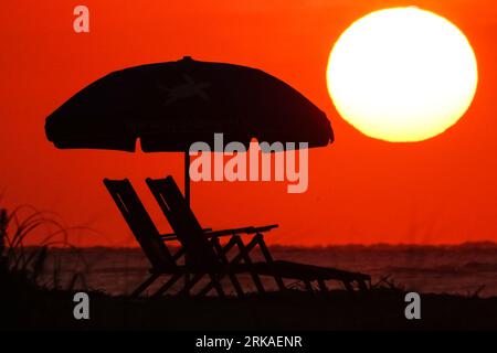 Isle Of Palms, United States. 24th Aug, 2023. An empty beach umbrella and chairs silhouetted by the sunrise over the Atlantic Ocean in the Charleston area, August 24, 2023 in Isle of Palms, South Carolina. Credit: Richard Ellis/Richard Ellis/Alamy Live News Stock Photo