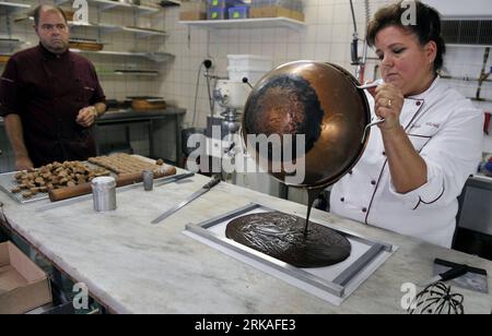 Bildnummer: 54343579  Datum: 24.08.2010  Copyright: imago/Xinhua Jannick Poncioni makes the chocolates by hand in Micheli Chocolate shop in Geneva, Aug. 24, 2010. The Micheli chocolate shop, founded in 1964 by Pierre Poncioni and Liliane Poncioni, parents of Dider and Jannick, is one of the most famous chocolate shops in Switzerland. Despite the domination of industrial methods, the shop insist using their traditional recipe: each piece of chocolate is made exclusively by hand, cut with a knife and carefully coated using a fork. (Xinhua/Yu Yang) (wh) SWITZERLAND-GENEVA-HANDMADE CHOCOLATE SHOP Stock Photo