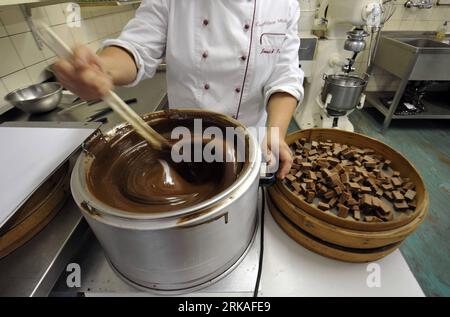 Bildnummer: 54343573  Datum: 24.08.2010  Copyright: imago/Xinhua Jannick Poncioni makes the chocolates by hand in Micheli Chocolate shop in Geneva, Aug. 24, 2010. The Micheli chocolate shop, founded in 1964 by Pierre Poncioni and Liliane Poncioni, parents of Dider and Jannick, is one of the most famous chocolate shops in Switzerland. Despite the domination of industrial methods, the shop insist using their traditional recipe: each piece of chocolate is made exclusively by hand, cut with a knife and carefully coated using a fork. (Xinhua/Yu Yang) (wh) SWITZERLAND-GENEVA-HANDMADE CHOCOLATE SHOP Stock Photo