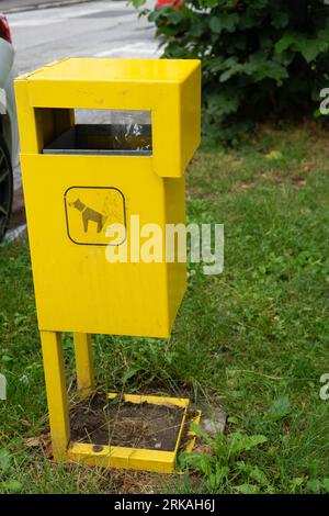 Im Sommer steht im Park ein gelber Abfallbehälter für Hunde. Umweltschutz, Tierpflegekonzept hochwertiges Foto. Stockfoto