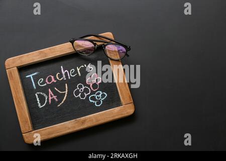 Tafel mit LEHRERTAG und Brille auf schwarzem Hintergrund Stockfoto