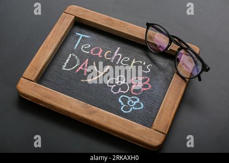 Tafel mit LEHRERTAG und Brille auf schwarzem Hintergrund Stockfoto