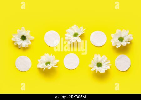 Composition with cotton pads and chamomile flowers on yellow background Stock Photo