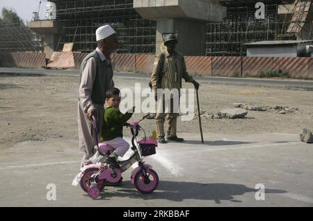 Bildnummer: 54529736 Datum: 12.10.2010 Copyright: imago/Xinhua (101012) -- SRINAGAR, 12. Oktober 2010 (Xinhua) -- Ein Kashmiri-Mann hilft einem Kind mit einem Dreirad als indischer paramilitärischer Soldat während einer Ausgangssperre in Srinagar, der Sommerhauptstadt des von Indien kontrollierten Kaschmirs am 12. Oktober 2010. Die Behörden haben am Dienstag in den von Indien kontrollierten Gebieten Kaschmirs, einschließlich Srinagar, eine strenge Ausgangssperre verhängt, um einen protestmarsch zu vereiteln, der von der Hardline-Separatistenallianz Hurriyat (Freedom) Conference einberufen wurde. Hunderte von Polizisten und paramilitärische Personen der Central Reserve Police Force (CRPF) in Indien Stockfoto