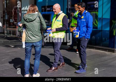 Auckland, New Zealand, 25 Aug, 2023. National Party Leader Christopher Luxon (C) with Auckland Central candidate Mahesh Muralidhar (R) collects for the Cancer Society Daffodil Day whilst campaigning for the General Election. Credit: David Rowland/Alamy Live News Stockfoto