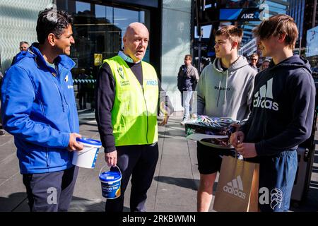Auckland, Neuseeland, 25. August 2023. Der Parteivorsitzende Christopher Luxon (C) und Mahesh Muralidhar (L) aus Auckland Central sammeln sich für den Daffodil Day der Cancer Society, während er für die Wahlen kandidiert. Quelle: David Rowland/Alamy Live News Stockfoto