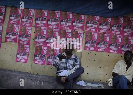 Bildnummer: 54680727  Datum: 26.11.2010  Copyright: imago/Xinhua (101127) -- PORT-AU-PRINCE, Nov. 27, 2010 (Xinhua) -- Haitian men sit next to a wall covered with posters of presidential candidate Michel Martelly in Port-au-Prince, Haiti, on Nov. 26, 2010. Haiti will hold presidential election on Nov. 28 amid cholera epidemic that has left at least 1,000 dead. (Xinhua/Str) (axy) HAITI-PRESIDENTIAL ELECTION-POSTERS PUBLICATIONxNOTxINxCHN Politik Wahlen Wahlkampf Haiti premiumd kbdig xsp 2010 quer o0 Präsidentschaftswahl, Wahlkampf, Wahlwerbung, Wahlplakat    Bildnummer 54680727 Date 26 11 2010 Stock Photo