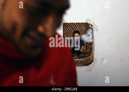 Bildnummer: 54769835  Datum: 24.12.2010  Copyright: imago/Xinhua (101225) -- WUQIAO, Dec. 25, 2010 (Xinhua) -- Twenty-six-year-old Amir from Egypt sticks his son s photo on the wall of his dormitory at Wuqiao acrobatic art school in Wuqiao County, north China s Hebei Province, Dec. 24, 2010. Under the Chinese government-sponsored exchange programs, twenty-four students from five African and Asian countries, including Egypt, Nigeria, Liberia, Mauritius and Myanmar, began in November their one-year training of acrobatics in Wuqiao Acrobatics Arts School, a vocational school well-known for its ac Stock Photo