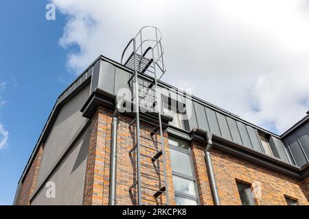 Dach eines renovierten alten Industriesteingebäudes mit Feuerschutzleiter im Freien. Stockfoto