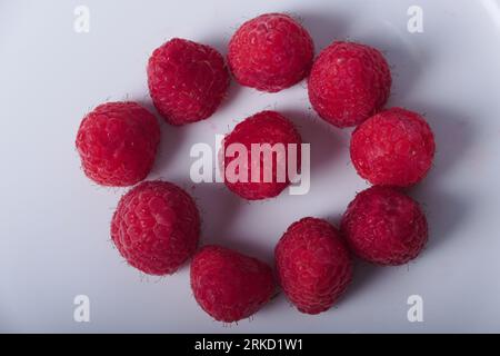 Buntes und geschmackvolles Muster mit köstlichen Himbeeren still Life 7 bereit für die Ewigkeit. Auf einer weißen Platte. Formen von Mustern, Linien und Konstruktionen. Stockfoto