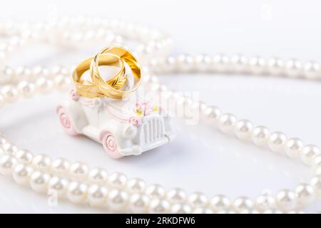 Zwei Eheringe auf einem kleinen Oldtimer mit Perlenkette. Stockfoto