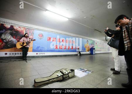 Bildnummer: 54945850 Datum: 22.02.2011 Copyright: imago/Xinhua (110223) -- PEKING, 23. Februar 2011 (Xinhua) -- Wan Xiuli, ein Straßenmusiker aus der südchinesischen Autonomen Region Guangxi Zhuang, spielt Gitarre und singt ein Lied für Fußgänger in einer Unterführung in Peking, 22. Februar 2011. Eine gute Anzahl von Straßenstärkern, von denen die meisten davon träumen, berühmt zu werden, treten gewöhnlich an öffentlichen Orten auf, während sie sich bemühen, mit den Schwierigkeiten des Lebens fertig zu werden. Derzeit hoffen mehr Basismusiker, ihre Träume über das Internet zu verwirklichen, wie Wang Xu, 44, und Liu Gang, 29, zwei Migrantinnen wo Stockfoto