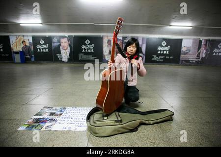 Bildnummer: 54945858  Datum: 22.02.2011  Copyright: imago/Xinhua (110223) -- BEIJING, Feb. 23, 2011 (Xinhua) -- Wan Xiuli, a grassroots street musician, packs up her guitar to perform elsewhere in an underpass in Beijing, Feb. 22, 2011. A good number of grassroots street musicians, most of whom dream of rising to fame, usually perform in public places while striving to cope with the hardships of life. Currently, more grassroots musicians hope to realize their dreams via the Internet, as Wang Xu, 44 and Liu Gang, 29, two migrant workers in Beijing and Xidan Girl , who used to busk in Beijing pe Stock Photo