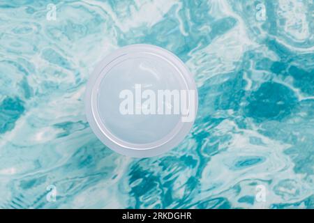 Gläschen mit Schönheitscreme und hellblauem Wasser. Feuchtigkeitsspendende Schönheitscreme, Hautpflege und Spa-Kosmetik. Draufsicht und Kopierbereich Stockfoto
